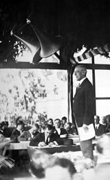 Präsident Woodrow Wilson (1856–1924) bei einer öffentlichen Rede. Die großen Aufnahmetrichter über ihm waren nötig, da es noch keine leistungsfähigen elektrischen Verstärker gab.